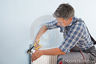 Plumber fixing radiator with wrench Stock Photo