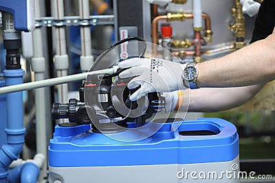 Plumber hands in gloves joining compact water filter to water tank of house water supply system Stock Photo