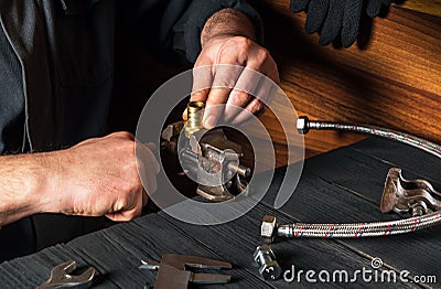 The plumber inserts the brass fittings into a vise. Close-up of a foreman is hand while working in workshop. Stock Photo