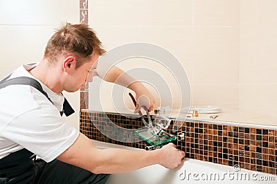 Plumber installing a mixer tap in a bathroom Stock Photo