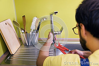 Plumber installing, repairing water tap in kitchen Stock Photo