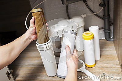 Plumber installs or change water filter. Replacement aqua filter. Repairman installing water filter cartridges in a kitchen. Clean Stock Photo