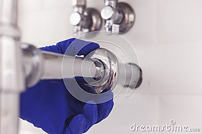 Plumber maintains chrome universal escutcheon on siphon pipe under the washbasin. Plumber at work in bathroom, plumbing Stock Photo