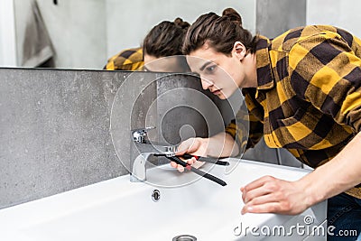 Plumber man fixing water tap with spanner in bathroom Stock Photo