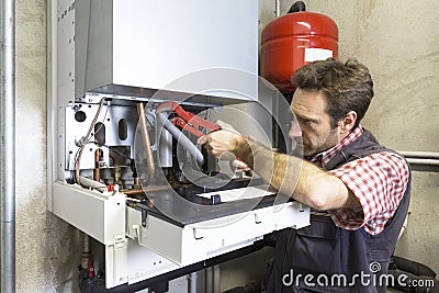 Plumber repairing a condensing boiler Stock Photo