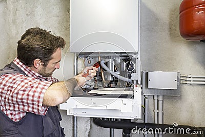 Plumber repairing a condensing boiler Stock Photo