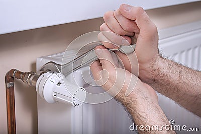 Plumber`s male hands hold a flat wrench by which they unscrew the temperature control valve. Stock Photo