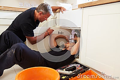 Plumber teaching an apprentice to fix a kitchen sink Stock Photo