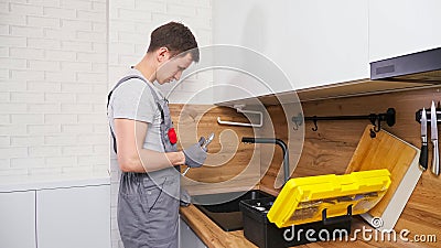 Plumber with toolbox comes to check and fix broken faucet Stock Photo