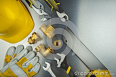 Plumber tools on brushed aluminum background with yellow helmet Stock Photo