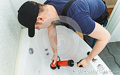 Plumber unclogging bathtub Stock Photo