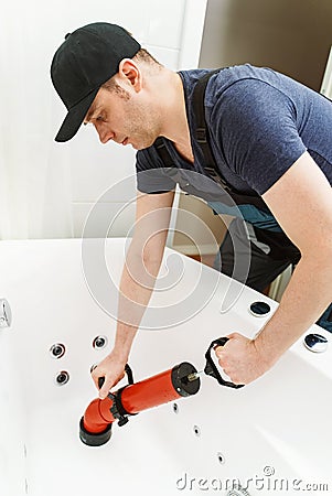 Plumber unclogging bathtub Stock Photo