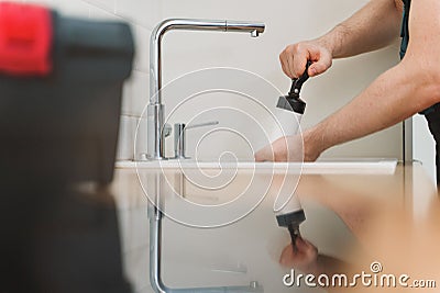 Plumber unclogging kitchen sink Stock Photo