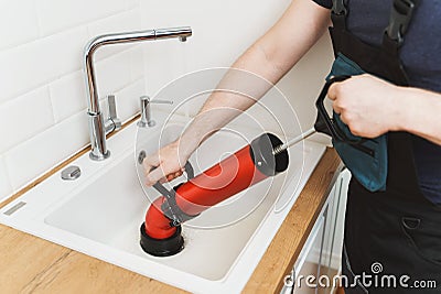 Plumber unclogging kitchen sink Stock Photo