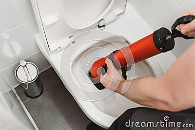 Plumber unclogging toilet Stock Photo