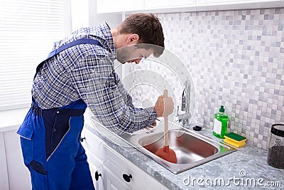 Plumber Using Plunger In Sink Stock Photo