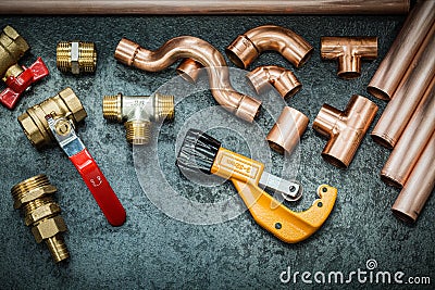 Plumbers tools copper pipes fittings pipe cutter and valwes on black background Stock Photo