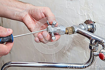 Plumbing repair, plumber unscrews handle kitchen faucet using ha Stock Photo