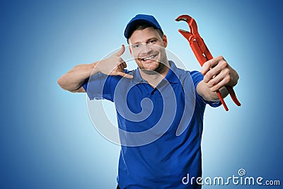 Plumbing services - plumber with wrench showing phone call gesture Stock Photo