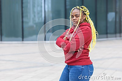 Plump, fat black African American serious girl with creative yellow hair, angry young woman crossing her hands Stock Photo