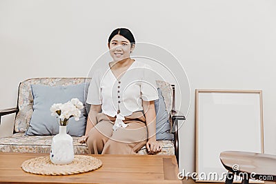 Plump and healthy housewife sitting in the home living room warm smiling, looking at the camera Stock Photo