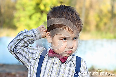 Plump little boy in shirt and bow tie thinks Stock Photo