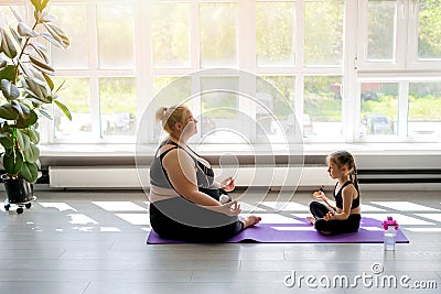 Plump mother and a fragile, thin daughter are doing yoga at home Stock Photo