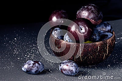 Plums in a coconut bowl on a dark background Stock Photo