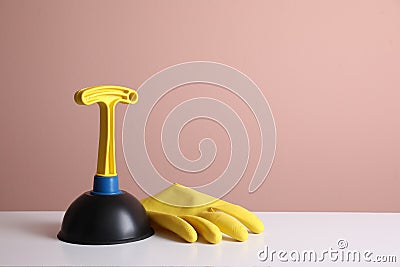 Plunger and rubber glove on white table against pink background. Space for text Stock Photo