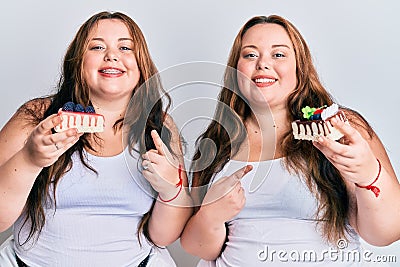 Plus size caucasian sisters woman holding slice of cake smiling happy pointing with hand and finger Stock Photo