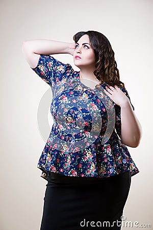 Plus size fashion model in floral blouse, fat woman on beige background Stock Photo