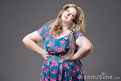 Plus size fashion model in floral dress, fat woman on gray background Stock Photo