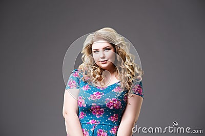 Plus size fashion model in floral dress, fat woman on gray background Stock Photo
