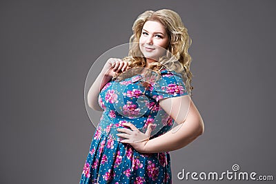 Plus size fashion model in floral dress, fat woman on gray background Stock Photo