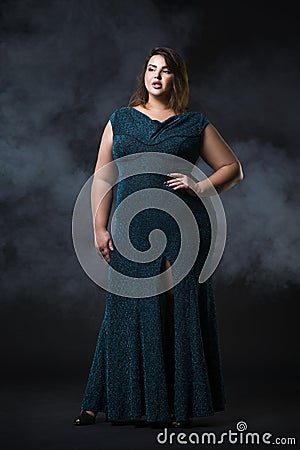 Plus size fashion model in green evening dress, fat woman on black background, overweight female body Stock Photo