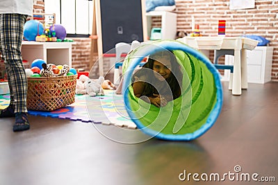 Plus size hispanic girl smiling confident crawling through tunnel toy at classroom Stock Photo