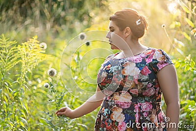 Plus size model in floral dress outdoors, beautiful fat woman with big breasts in nature Stock Photo