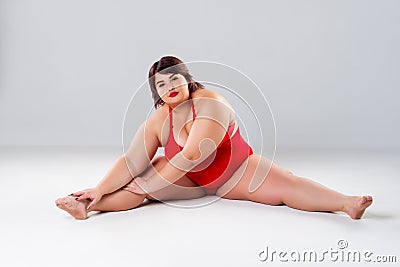 Plus size model in red lingerie, fat woman in underwear on gray background, body positive concept Stock Photo