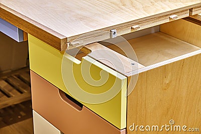 Plywood desk with multi color drawers during assembly. Close-up Stock Photo