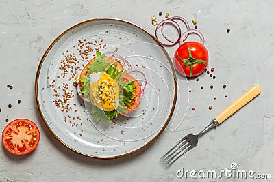 Poached egg sandwich with mustard sauce, tomatoes and onions on a gray plate. eggs Benedict. Overhead, horizontally, with space Stock Photo