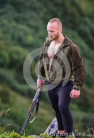 Poaching concept. Poacher stand on edge of cliff. Hunter poacher looking for victim. Hunter with rifle nature Stock Photo