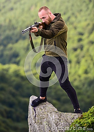 Poaching concept. Poacher stand on edge of cliff. Hunter poacher looking for victim. Hunter with rifle nature Stock Photo