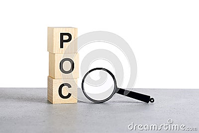POC - Proof of Concept - text wooden cube blocks and magnifying glass on grey table Stock Photo