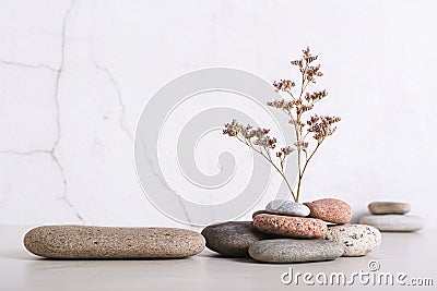 A podium made of smooth sea stone and a dried flower from a pile of stones on the table Stock Photo