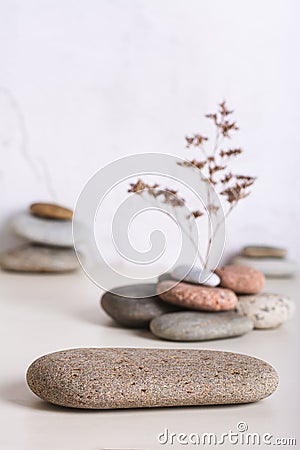 A podium made of smooth sea stone and a dried flower from a pile of stones vertical view Stock Photo