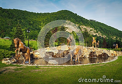 Poiana lui Caliman Park in Caciulata, Romania. Artesian well with horse statues. Stock Photo