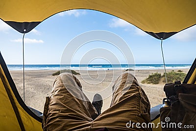 Point of view with laying man inside a tent enjoying relax and adventure in free camping with beach and sea blue sea and sky Stock Photo