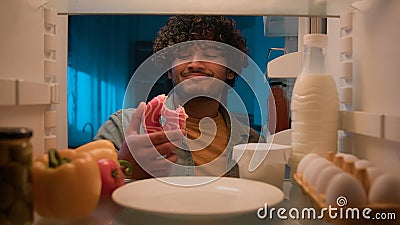 Point of view POV from inside refrigerator hungry Indian man Arabian guy male at night kitchen open fridge want eat take Stock Photo