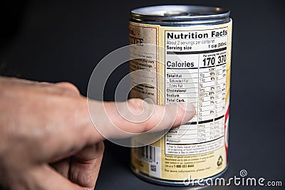 Pointing at the Nutritional facts on a grocery Can of food. Stock Photo