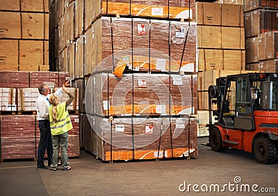 Pointing to greater heights. Two colleagues standing in a warehouse and pointing up to the goods close to a fork lift.. Stock Photo